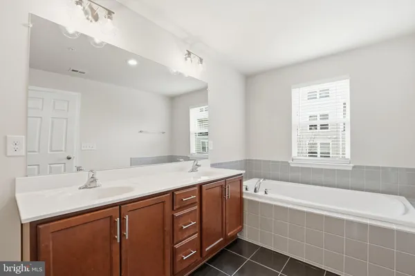 a spacious bathroom with a tub sink and mirror