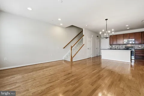 a view of a kitchen and an empty room with wooden floor