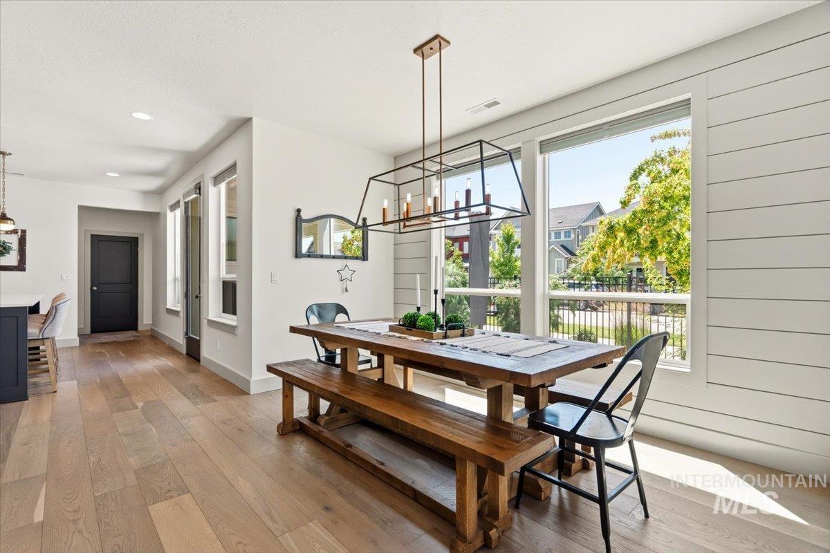 3794 South Single Tree Avenue Boise, ID 83716 - Photo 15 of 50 Open-concept interior featuring wood-finish flooring, a linear chandelier, ample natural light from large windows, recessed ceiling lights, and shiplap wall detailing