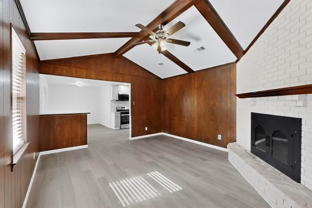 a view of an empty room with wooden floor and a fireplace