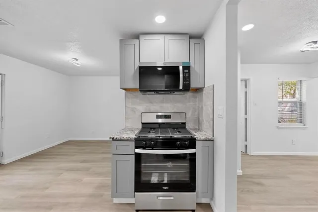 a kitchen with granite countertop a stove and a microwave