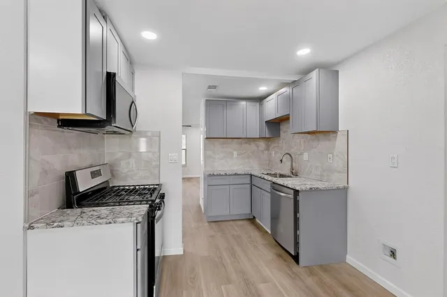 a kitchen with stainless steel appliances a sink stove and cabinets
