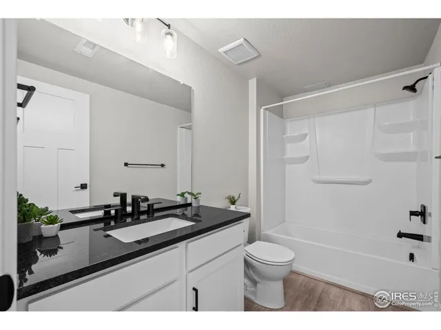 a bathroom with a granite countertop sink a toilet a mirror and shower