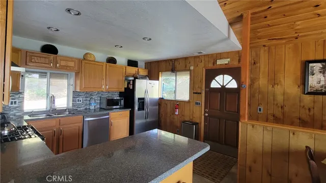 a kitchen with stainless steel appliances granite countertop a refrigerator a stove and a sink with wooden floor
