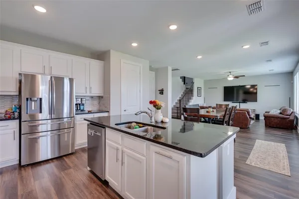 a kitchen with a refrigerator a sink dishwasher a stove and white cabinets with wooden floor