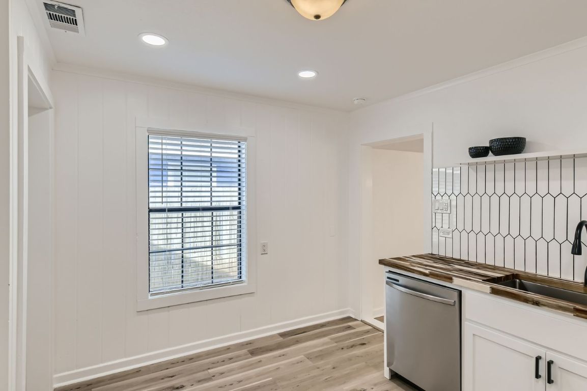 902 Hackberry Street Taylor, TX 76574 - Photo 11 of 29 Kitchen featuring stainless steel dishwasher, white cabinetry, light wood-style flooring, recessed lighting, and ornamental molding