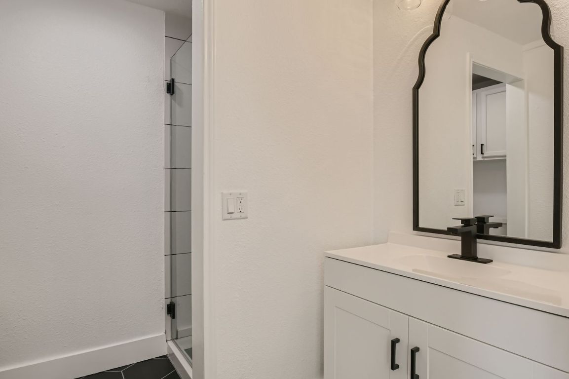902 Hackberry Street Taylor, TX 76574 - Photo 18 of 29 Bathroom with vanity, a shower stall, dark tile patterned floors, and a textured wall