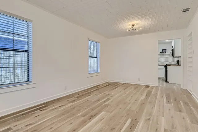 a view of empty room with wooden floor and fan