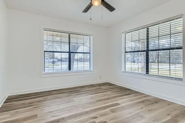a view of an empty room with a window and wooden floor