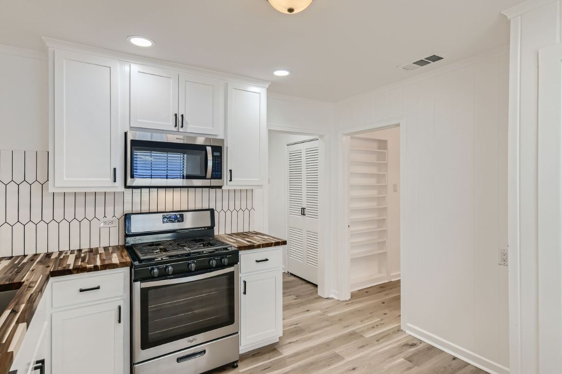 902 Hackberry Street Taylor, TX 76574 - Photo 9 of 29 Kitchen with stainless steel appliances, white cabinetry, recessed lighting, light wood-style flooring, and crown molding
