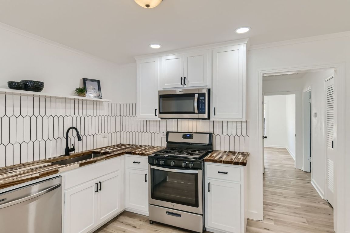 902 Hackberry Street Taylor, TX 76574 - Photo 10 of 29 Kitchen featuring stainless steel appliances, white cabinets, open shelves, recessed lighting, and light wood-type flooring