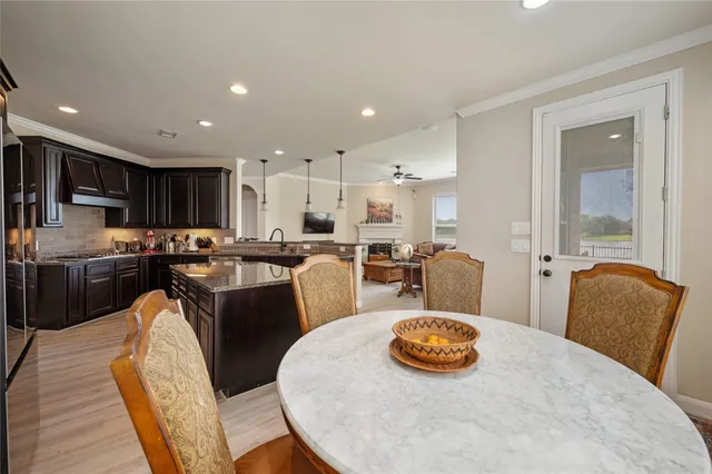 a kitchen with stainless steel appliances granite countertop a stove a refrigerator a kitchen island a table and chairs