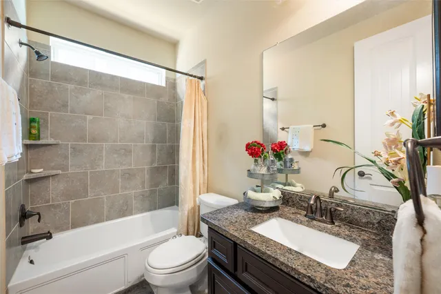 a bathroom with a granite countertop sink a toilet and shower