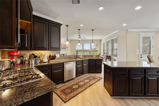 a kitchen with stainless steel appliances granite countertop a stove a sink dishwasher and a refrigerator