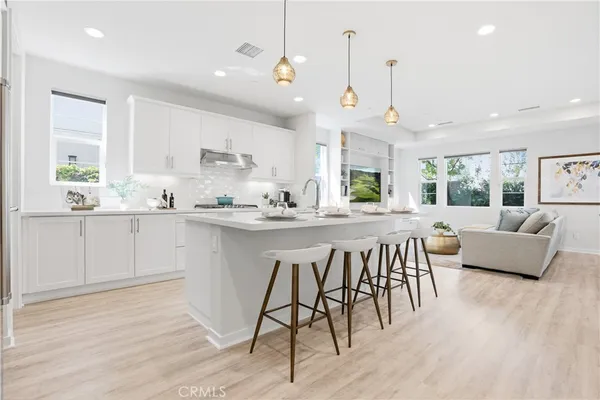 a kitchen with stainless steel appliances granite countertop a stove a sink a dining table and chairs with wooden floor
