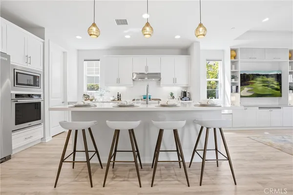 a kitchen with stainless steel appliances kitchen island granite countertop a dining table chairs and white cabinets