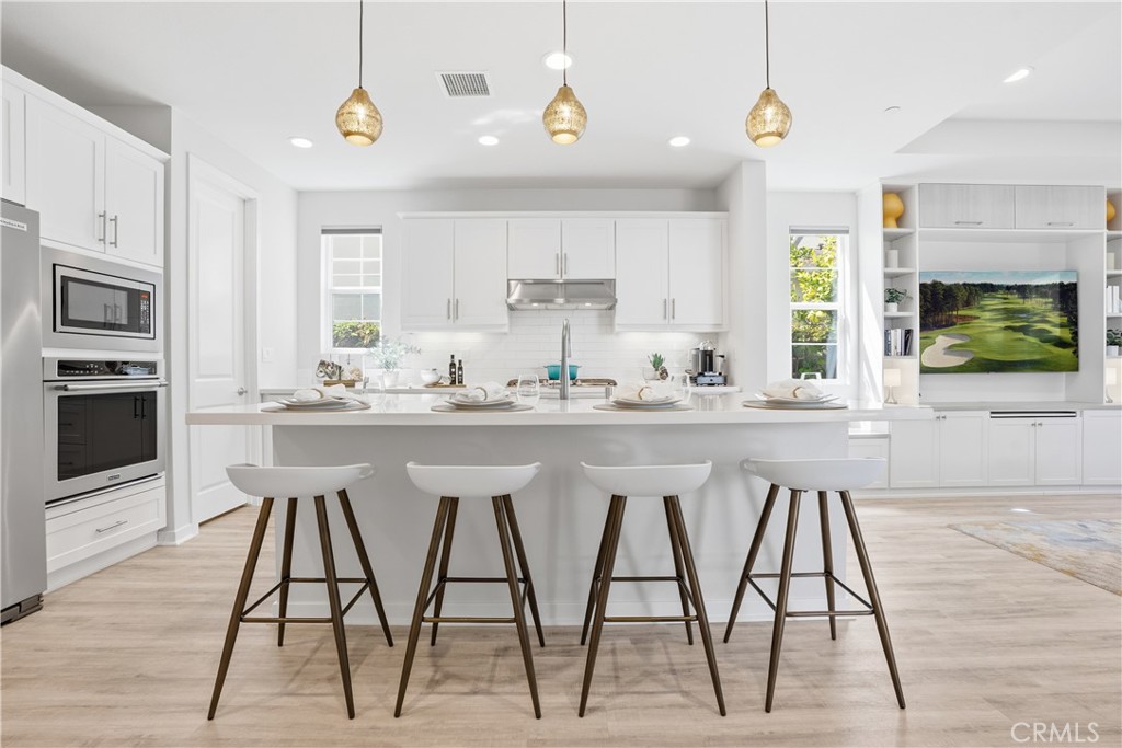 22 Jarano Street Rancho Mission Viejo, CA 92694 - Photo 4 of 75 a kitchen with stainless steel appliances kitchen island granite countertop a dining table chairs and white cabinets