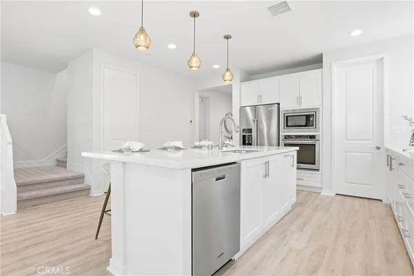 a large white kitchen with a large window a sink and stainless steel appliances