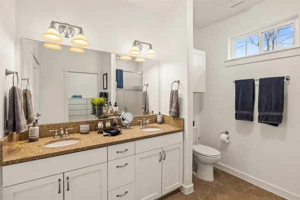 a bathroom with a granite countertop toilet sink and mirror