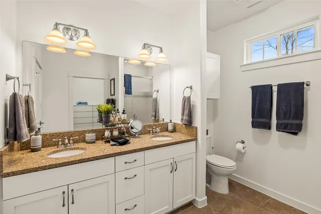 a bathroom with a granite countertop toilet sink and mirror