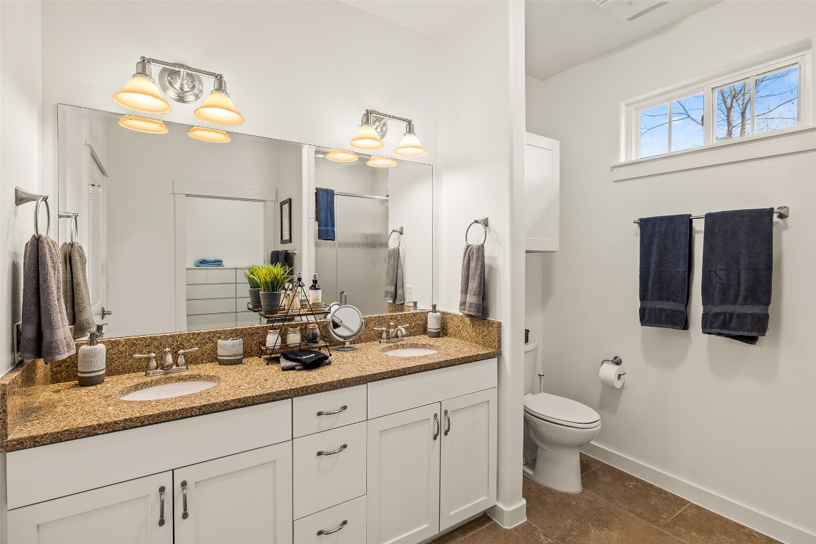 435 Hays Street Dripping Springs, TX 78620 - Photo 17 of 36 a bathroom with a granite countertop toilet sink and mirror