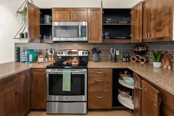 a kitchen with stainless steel appliances granite countertop a stove a microwave and wooden cabinets