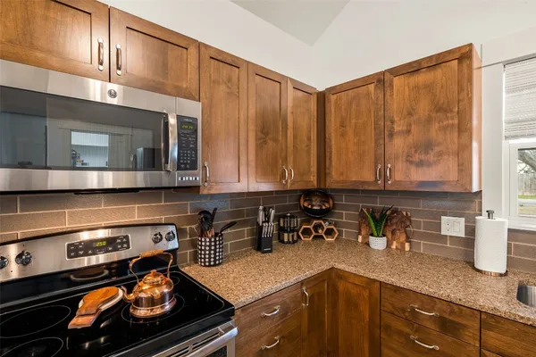 a kitchen with stainless steel appliances granite countertop a stove a sink and a microwave