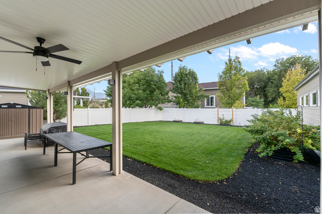 886 River Ridge Lane Spanish Fork, UT 84660 - Photo 23 of 31 Covered concrete patio with ceiling fan, expansive fenced lawn, and perimeter landscaping