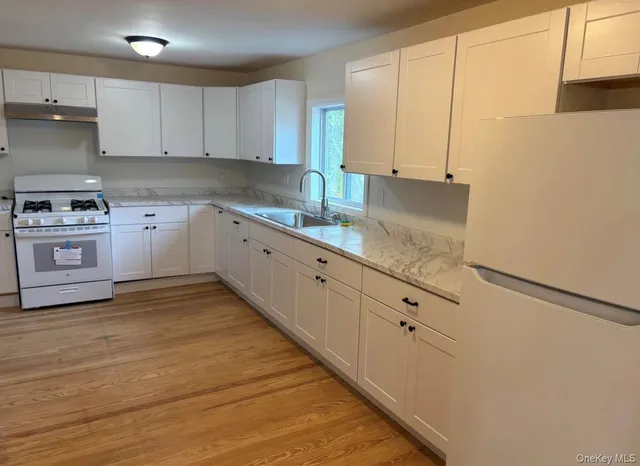a kitchen with granite countertop white cabinets and white appliances
