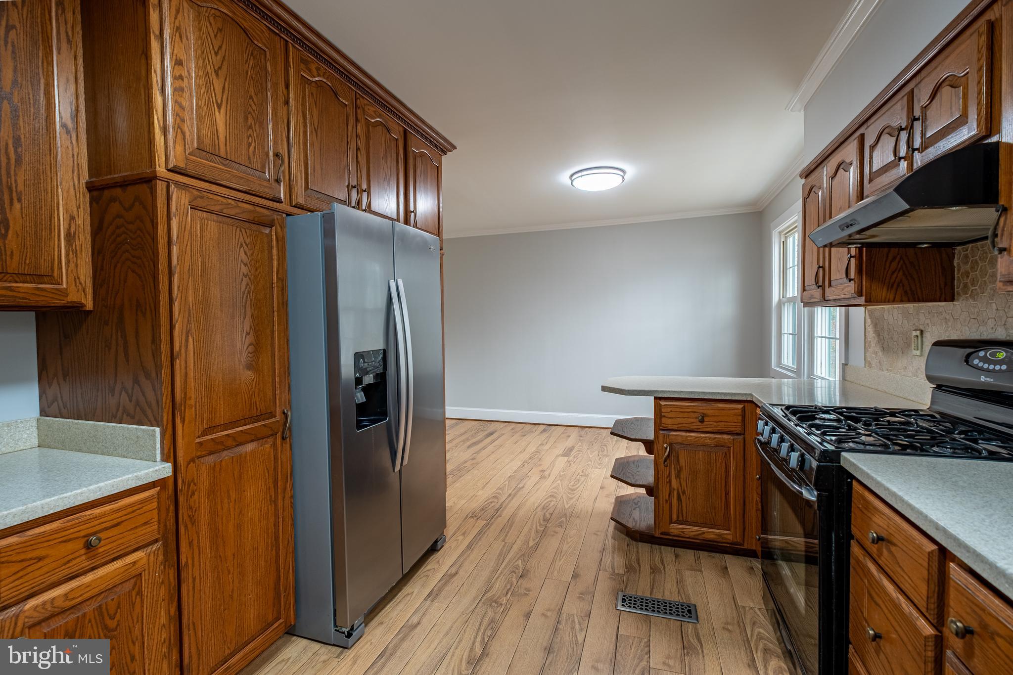 5680 Bryantown Road Bryantown, MD 20617 - Photo 7 of 33 a kitchen with stainless steel appliances granite countertop a refrigerator a stove and a sink with wooden cabinets