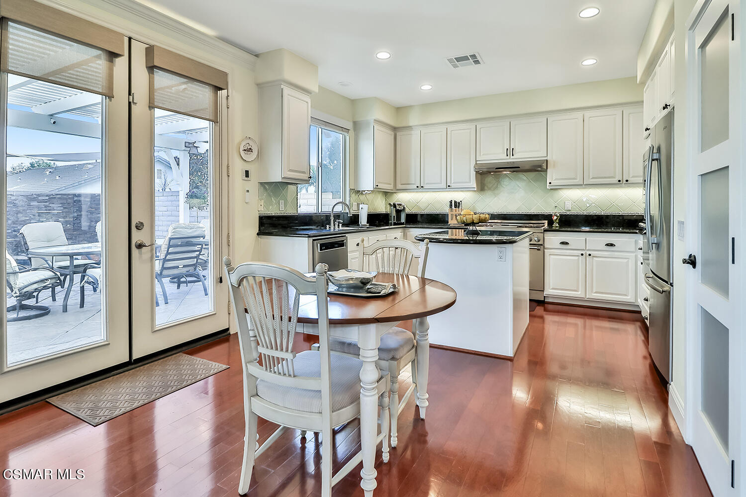 4904 Promenade Street Simi Valley, CA 93063 - Photo 19 of 63 a kitchen with stainless steel appliances granite countertop a stove top oven a refrigerator a sink and white cabinets with wooden floor