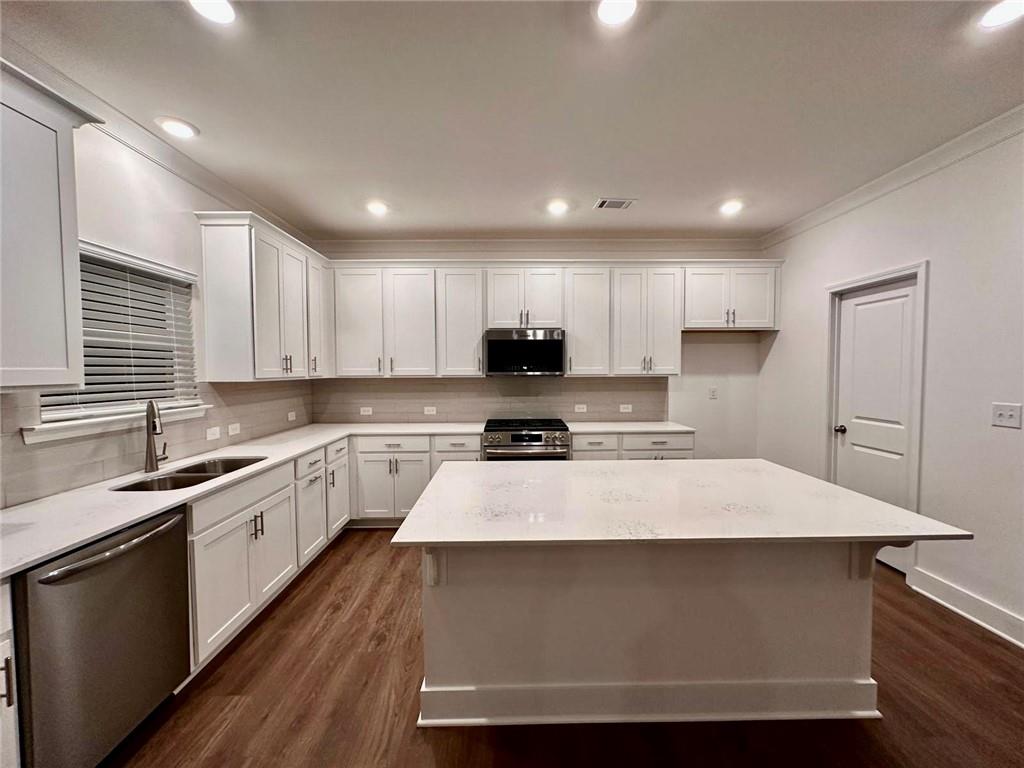 537 Hyde Rdg Trail Loganville, GA 30052 - Photo 3 of 23 a white kitchen with wooden floor and black stainless steel appliances