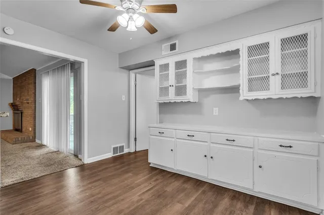an empty room with a chandelier fan and windows