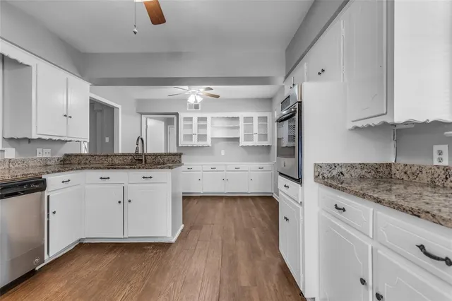 a kitchen with granite countertop white cabinets white appliances a sink and a window