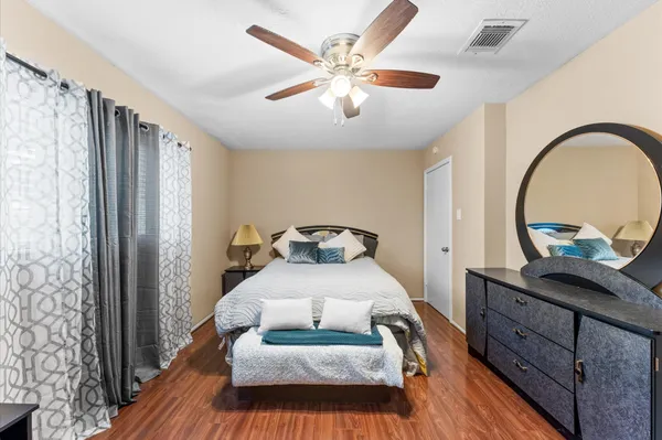 a bedroom with a bed and a dresser with wooden floor