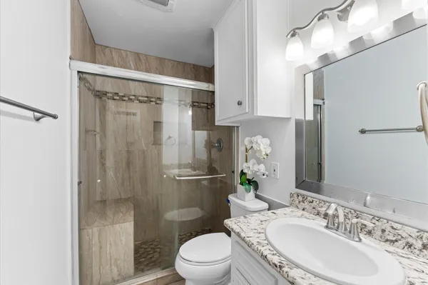 a bathroom with a granite countertop toilet a sink and a mirror