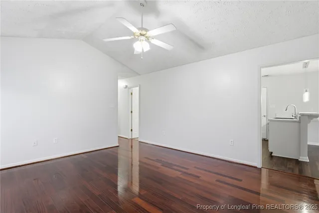 an empty room with wooden floor and fan