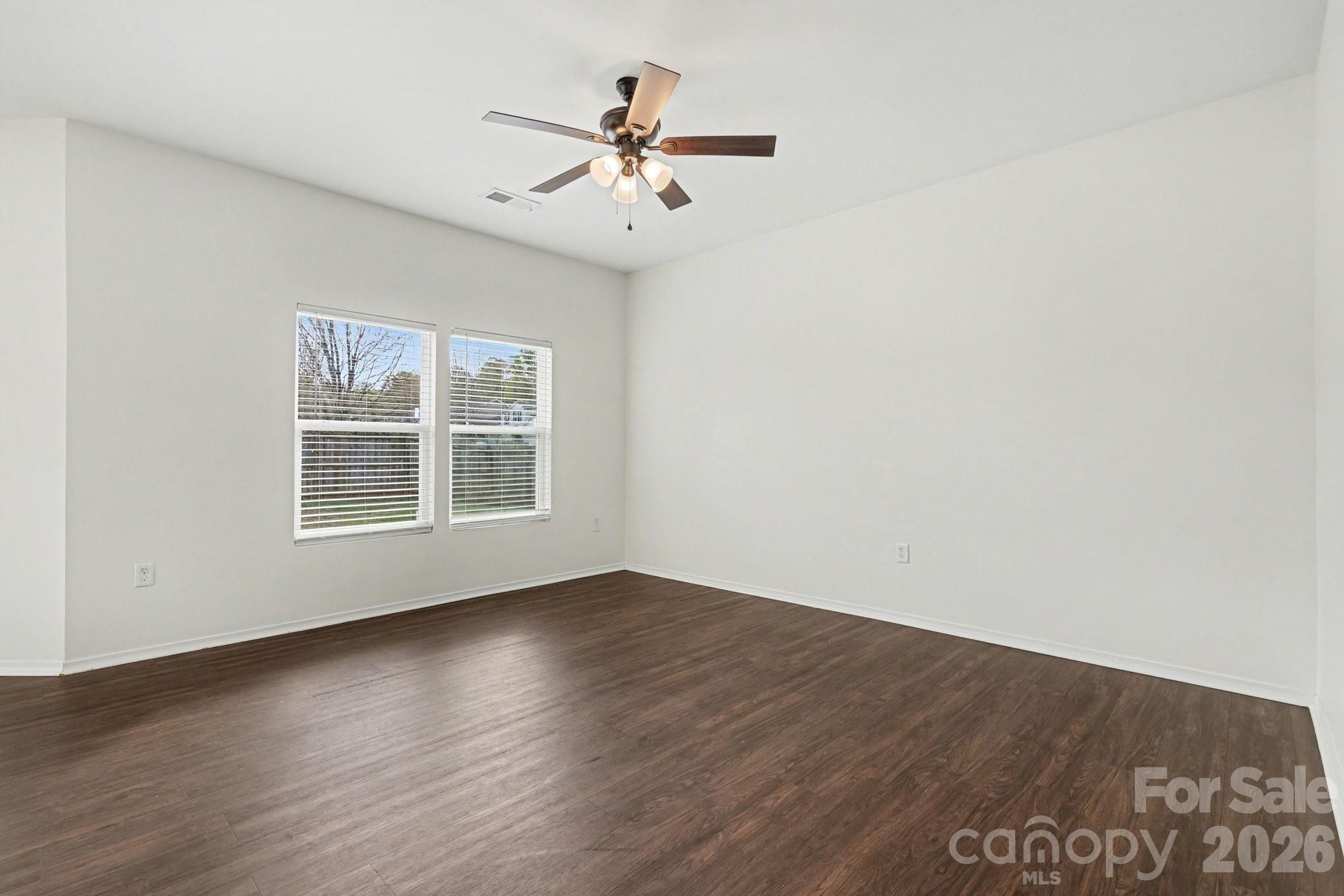 4400 Kiddle Lane Monroe, NC 28110 - Photo 6 of 28 an empty room with wooden floor chandelier fan and windows