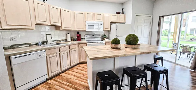 a kitchen with stainless steel appliances granite countertop a table chairs sink and cabinets