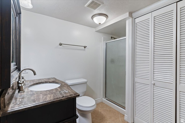 2350 South Highway 89, Unit 4 Perry, UT 84302 - Photo 17 of 30 Full bathroom featuring vanity, light tile patterned floors, a closet, a stall shower, and a textured ceiling