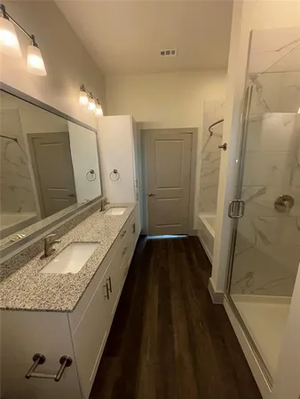 a bathroom with a granite countertop sink a mirror and shower