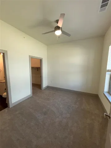 an empty room with a ceiling fan and window
