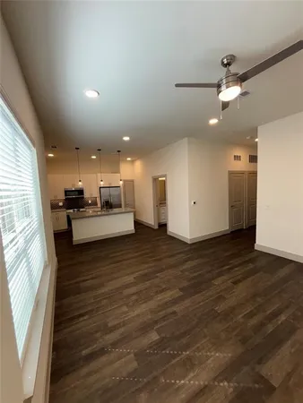 an empty room with wooden floor a ceiling fan and windows