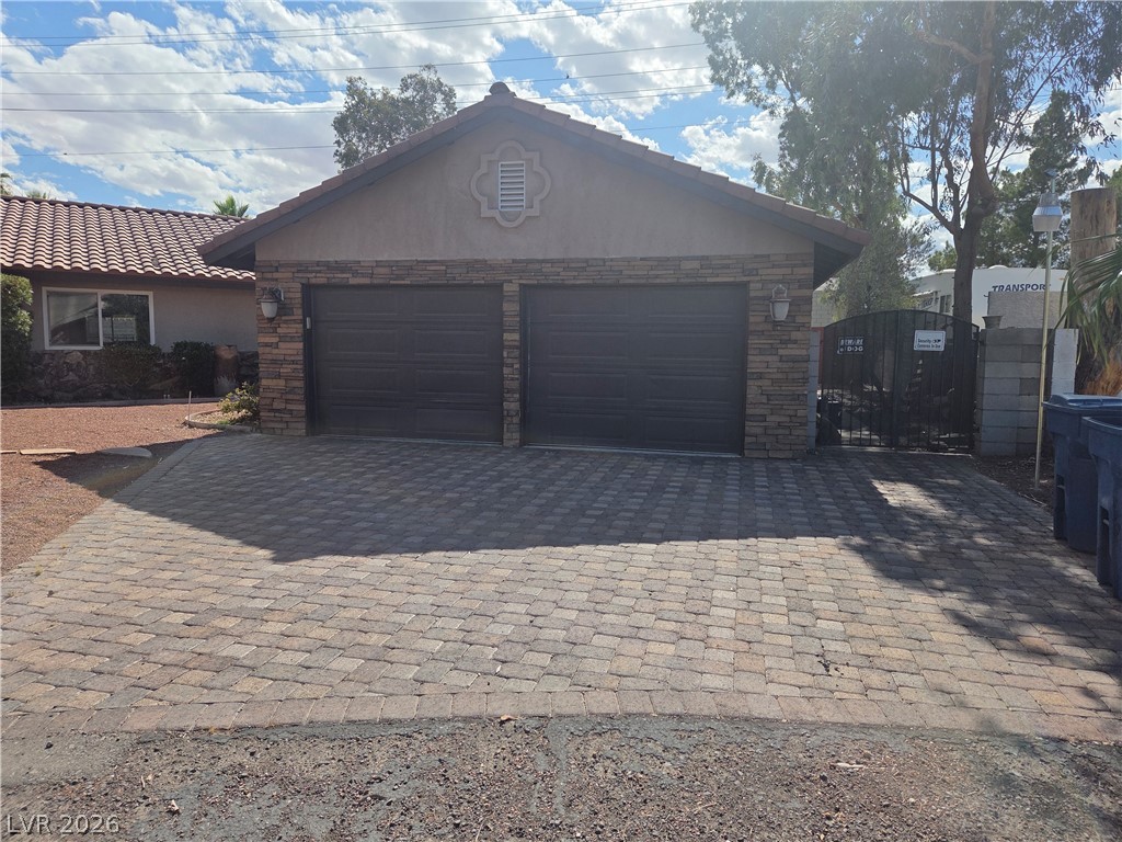 3381 Westwind Road Las Vegas, NV 89146 - Photo 3 of 52 A striking garage entry with stone accents and a patterned paver driveway.