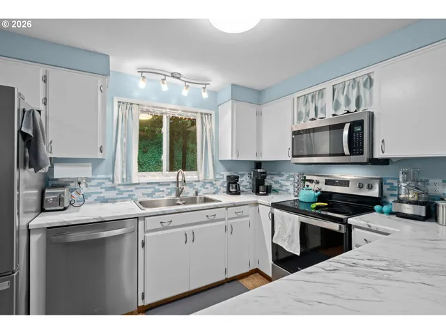 a kitchen with kitchen island granite countertop a sink stainless steel appliances and white cabinets