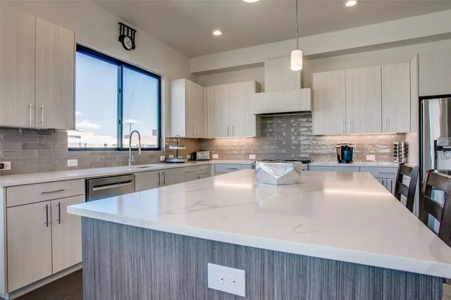 a large kitchen with granite countertop a large counter top stainless steel appliances and cabinets
