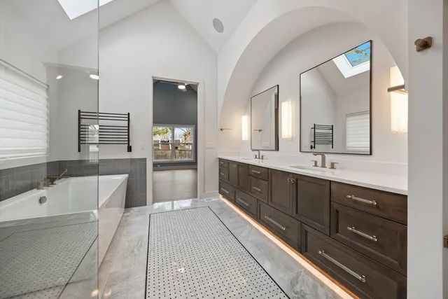 a spacious bathroom with a double vanity sink large mirror and a bathtub
