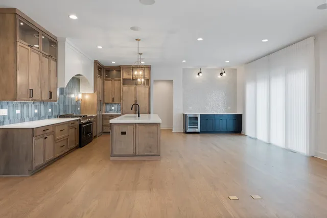 a large kitchen with a large counter top a sink stainless steel appliances and cabinets