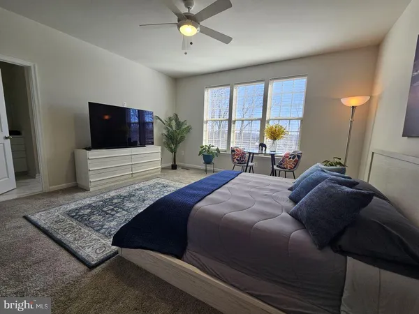 a bedroom with a bed a couch and a flat screen tv