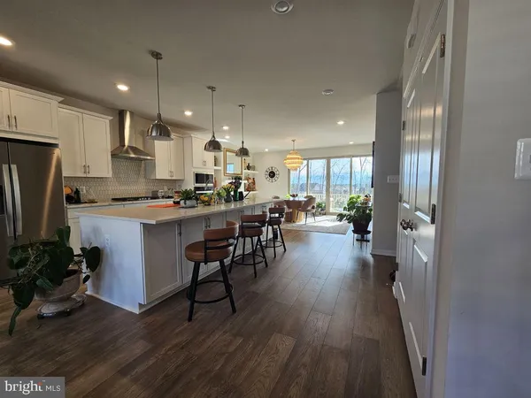 a kitchen with stainless steel appliances a dining table chairs refrigerator and cabinets